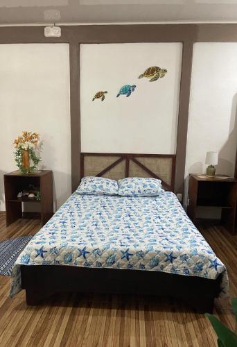 a bed in a room with three paintings on the wall at Villas Ela en Bahía Ballena,Uvita Hermosas habitaciones privadas grandes, piscina, cocina, jacuzzi, aire acondicionado, tv y baño privado in Uvita