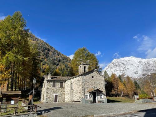 an old stone church with a mountain in the background at Sabbionaccio Apartments & Spa in Chiesa in Valmalenco
