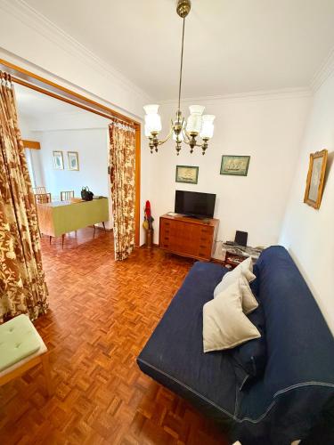 a living room with a blue bed and a couch at Casa da Mariazinha in Costa da Caparica