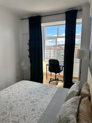 a bedroom with a bed and a desk and a window at Hostel Nosso Lar in Odivelas