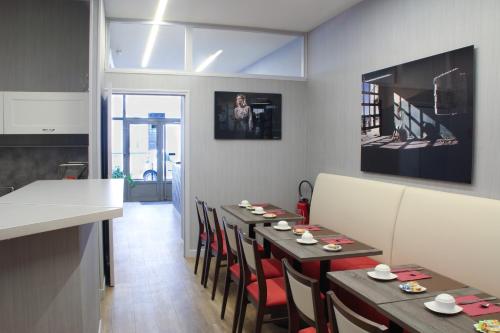 a dining room with tables and chairs and a kitchen at Hôtel De France in Boulogne-Billancourt