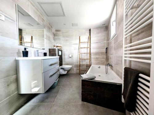 a bathroom with a tub and a sink and a toilet at Villa plein Sud, clim et piscine, 6 à 8 personnes in Boisseron