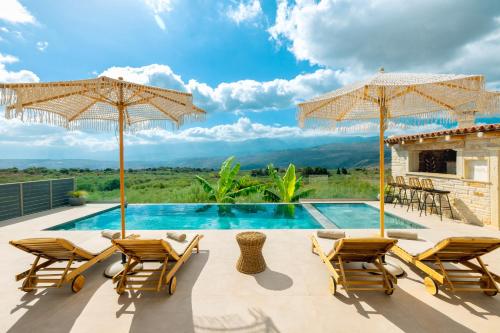 a villa with a swimming pool with chairs and umbrellas at Elegant Villa with Pool & Views in Áptera