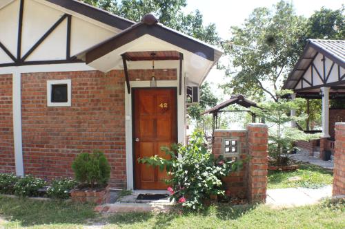 a brick house with a wooden door in a yard at Umang-umang Chalet in Kampong Tanjong Dahan