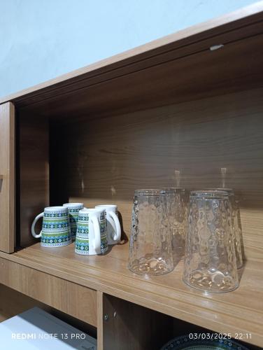 two glasses and mugs sitting on a shelf at 10 minutos de UNITEC Apartamento Peatonal 2 Habitaciones in Tegucigalpa