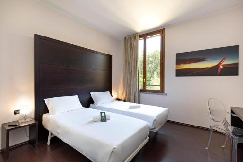 a hotel room with two beds and a window at B&B HOTEL Malpensa Lago Maggiore in Vergiate