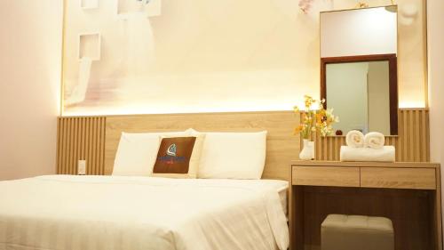 a bedroom with a white bed and a mirror at Trung Đông Hotel in Can Tho
