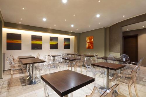 a restaurant with tables and chairs and paintings on the wall at B&B HOTEL Malpensa Lago Maggiore in Vergiate