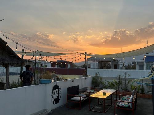 a person standing on a rooftop with a table and chairs at Monkey Toe Guesthouse in Chiang Mai