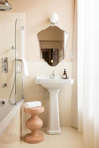 a bathroom with a sink and a toilet and a mirror at Le Charmant Hôtel in Saint-Ouen