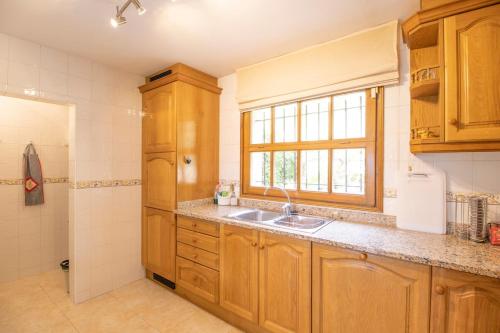 a kitchen with wooden cabinets and a sink and a window at Villa Anna- Calonge, Costa Brava in Calonge