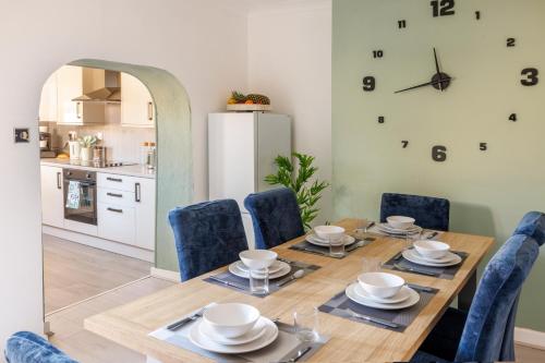 a dining room with a table and chairs and a clock on the wall at Columbia - Sleeps 5, WiFi, Parking, Netflix, Near Observatory in Sutton in Ashfield