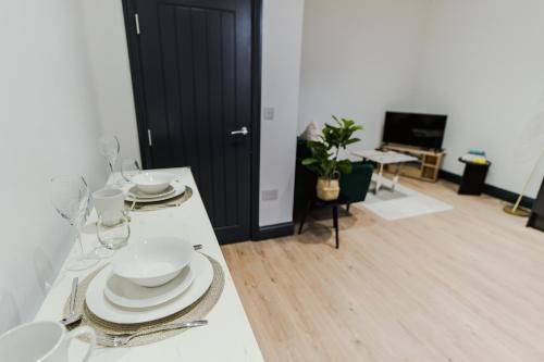 a white table with plates and glasses on it at Charming & Cosy 2 BR Flat, Fast Wifi -Sleeps 5 in Leeds