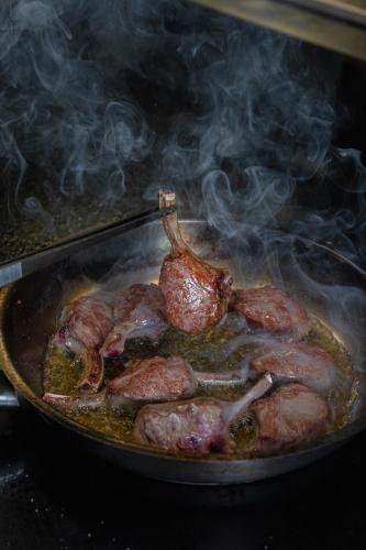 a pan of meat cooking in a grill with smoke at Hotel Il Castagno in Mugena