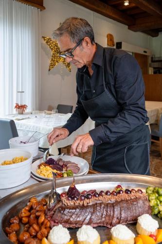 a man preparing food on a table with plates of food at Hotel Il Castagno in Mugena