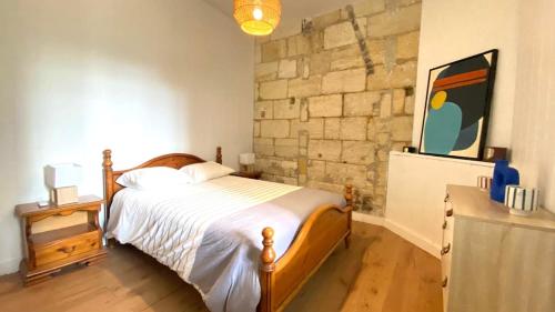 a bedroom with a bed and a stone wall at Charmant T2 avec Jardin, Barrière St-Genes in Talence
