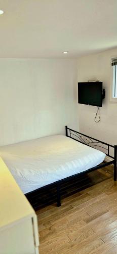 a bed in a room with a tv on the wall at Hameau de Soissons in Billy-sur-Aisne