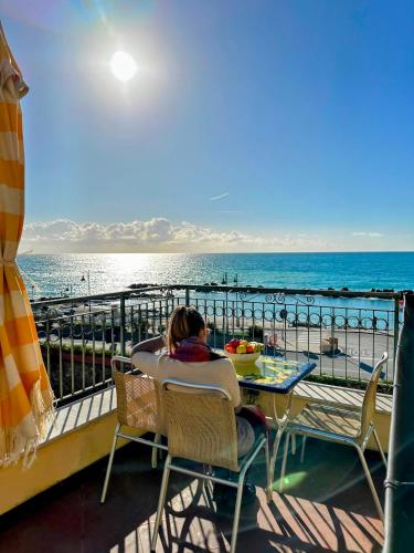 a woman sitting at a table looking at the ocean at Giada in Moneglia
