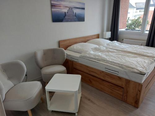 a bedroom with a bed and a chair at Wohnung Sonnenschein inkl Strandkorb vom 01 05-15 09 in Grömitz