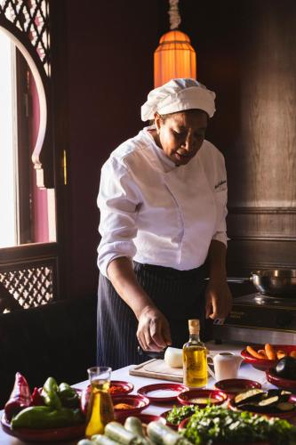 a woman standing in a kitchen preparing food at Riad Fes - Relais & Châteaux in Fès