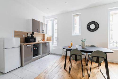 une cuisine avec une table et des chaises et un réfrigérateur blanc dans l'établissement Appartement 60m2 refait a neuf - Paris 12 - 4p, à Paris