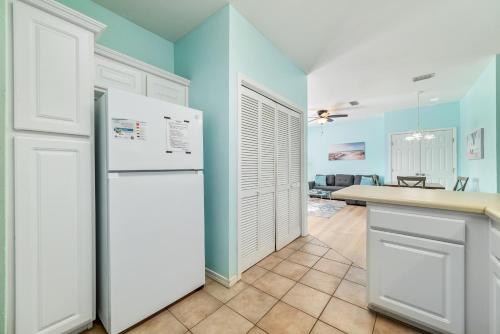 a kitchen with blue walls and a white refrigerator at Charming Condo Steps from the Beach & Lagoon! in Gulf Shores