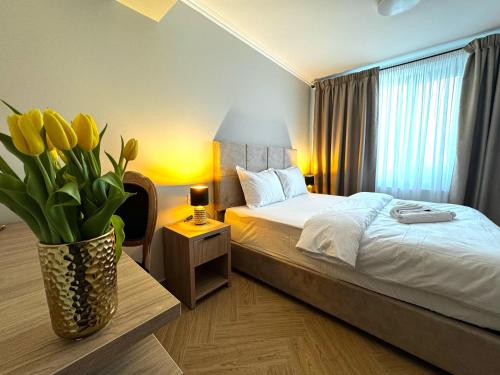 a bedroom with a bed with a vase of yellow flowers at Tempo Boutique in Buzau