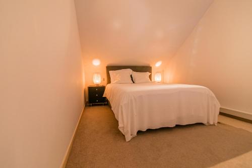 a bedroom with a white bed and two lamps at B&B Villa Curtricias in Kortessem