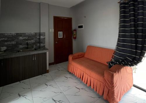 a living room with an orange couch and a sink at Mgf Franz Pension House in Bogo