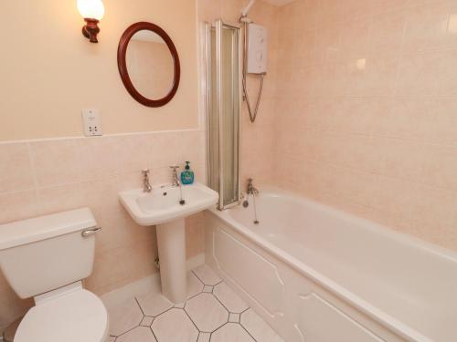 a bathroom with a toilet and a sink and a tub at The Smithy in Wooler