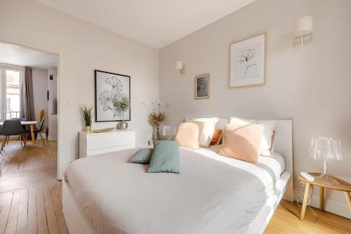 une chambre blanche avec un grand lit blanc avec des oreillers dans l'établissement Nancy Ville, à Nancy