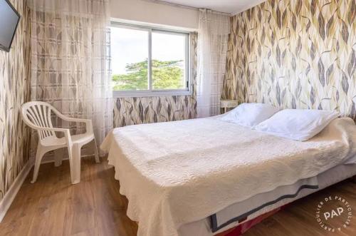 a bedroom with a bed and a chair and a window at Appartement avec vue sur la mer à La Baule 62 m² tout équipé in La Baule