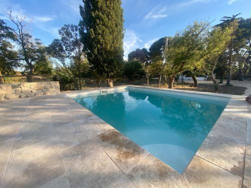 une piscine avec de l'eau bleue dans une cour dans l'établissement Le studio de la Bonne Aventure, à Saint-Mitre-les-Remparts