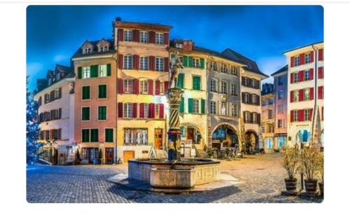 a group of buildings with a fountain in a street at Casa Jean-Jacques Rousseau in Biel