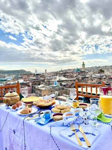 a table with food on it with a view of a city at Riad Hamad Tijani in Fès