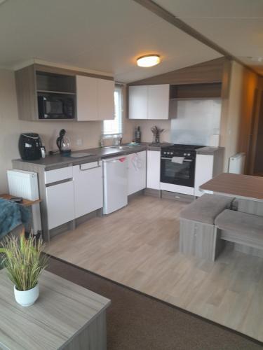 a large kitchen with white cabinets and a table at L83 amazing holiday home in Mablethorpe
