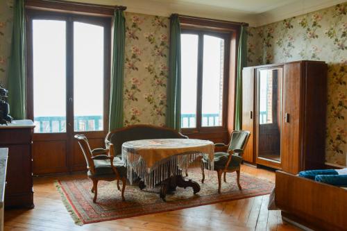 une salle à manger avec une table, des chaises et des fenêtres dans l'établissement Villa d'exception vue sur mer, 9 chambres, à Trouville-sur-Mer