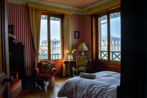 - une chambre avec un lit et un chat assis dans une chaise dans l'établissement Villa d'exception vue sur mer, 9 chambres, à Trouville-sur-Mer