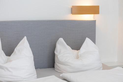 a bed with white pillows and a lamp at Hotel Seebrücke in Lubmin