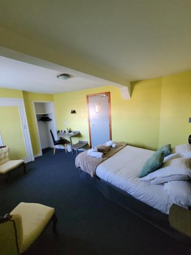a hotel room with a large bed and a desk at Hotel Logis Au Moyne de Saire in Réville
