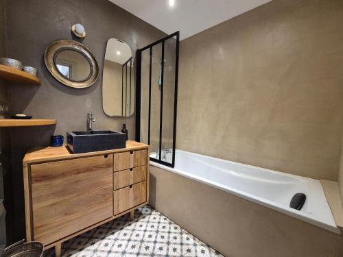 une salle de bain avec une baignoire, un lavabo et un miroir dans l'établissement Plein centre ville, Sublime appartement avec terrasse - Bourg Saint Maurice, à Bourg-Saint-Maurice