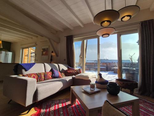 un salon avec un canapé et une grande fenêtre dans l'établissement Plein centre ville, Sublime appartement avec terrasse - Bourg Saint Maurice, à Bourg-Saint-Maurice
