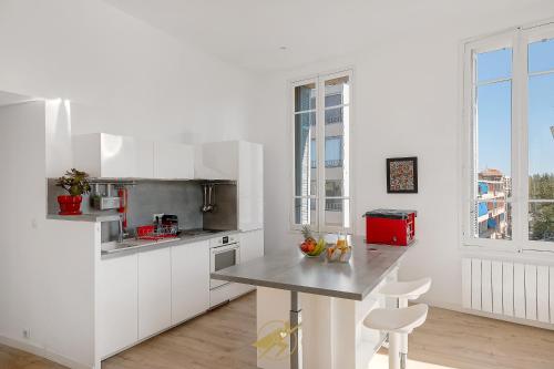 une cuisine avec des armoires blanches et un comptoir dans l'établissement Spacieux et lumineux - Coeur de quartier Gare de Hyeres - Wifi Fibre, à Hyères