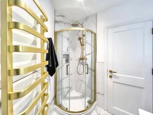 a bathroom with a shower and a gold mirror at Sunny Central 3BR Brighton Retreat in Brighton & Hove