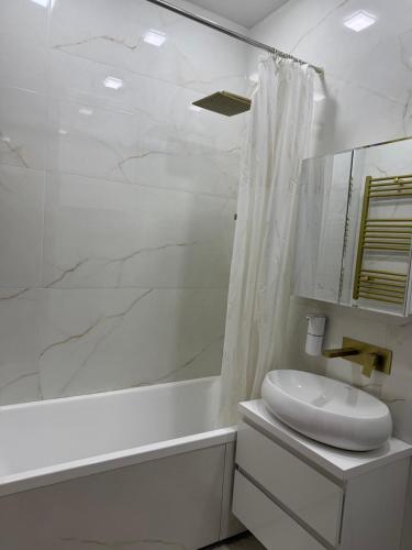 a white bathroom with a sink and a shower at Апартаменты в центре Худжанда in Khujand