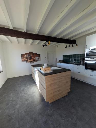 une grande cuisine avec des placards blancs et un îlot en bois dans l'établissement Gîte des Petits Prés, à La Neuville-aux-Joûtes