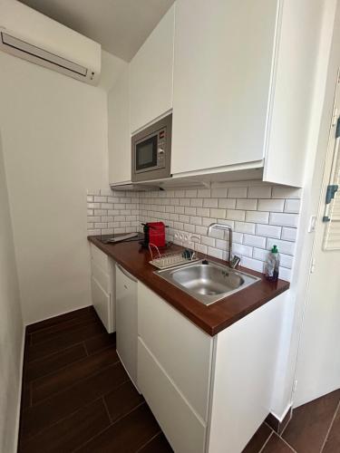 une cuisine avec un évier et un micro-ondes dans l'établissement Agréable Studio Rénové avec place de parking, à Bandol