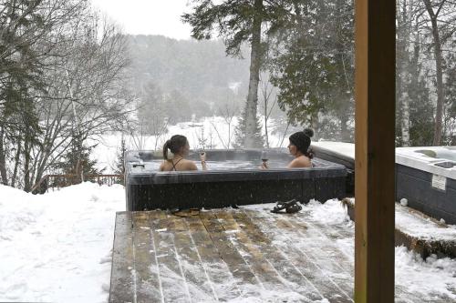 two women in a bath tub in the snow at Front RIVER private BEACH 2 HOT TUBS 15 p SAUNA in Labelle