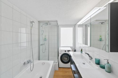 a bathroom with two sinks and a shower and a washing machine at book2stay - Apartments Herisau in Herisau