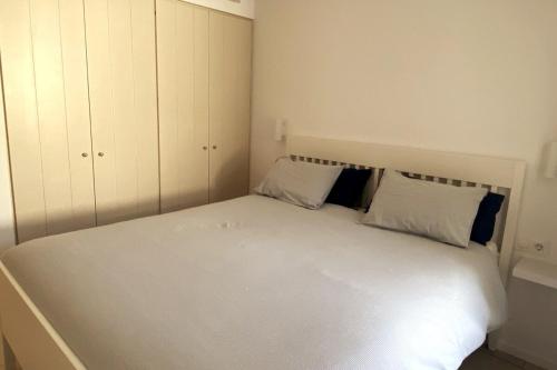 a small bedroom with a white bed with two pillows at Apartament Cadaqués in Cadaqués